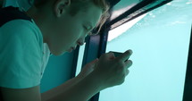 Boy on phone while on a boat with water at the window