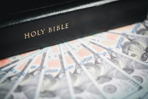Bible on top of one hundred dollar bills