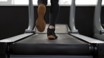 Closeup of legs man jogging on treadmill in gym, slow motion.