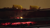 Corn and chicken cooking on a hot charcoal grill