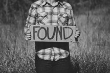 Man holding "Found" cardboard sign