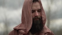 Jesus Christ, bible prophet (Noah, Moses, Elijah, John the Baptist, Abraham), religious, pious man or nomad traveler dressed in middle eastern, brown robes, tunic and shroud or hood standing alone in cinematic, slow motion in the wilderness temptation by the Devil or Satan for 40 days and 40 nights.