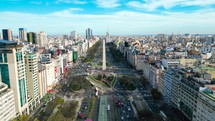 Panoramic Aerial drone view of Buenos Aires obelisk on avenida de Julio in Buenos Aires, Argentina. Shows buildings and skyscrapers with car traffic in the Street below.
