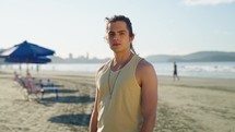 Man, beach and serious face for portrait, summer vacation outdoor. White man with ocean for traveling break
