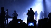 production crew and actors walking around a dark set 