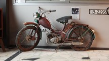 Static shot of an Old Simson SR2 Moped with rust inside a museum gallery. 