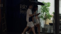 People walking by a store front with umbrellas