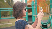 grandmother filming her granddaughter on the playground 