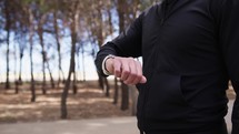 Hand Of A Man Dressed In Black Checks The Smartwatch