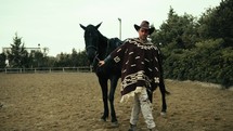 Cowboy walk in the ranch with his black horse