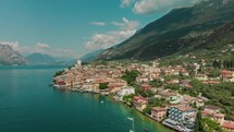 drone flies towards medieval town with church on a large lake
