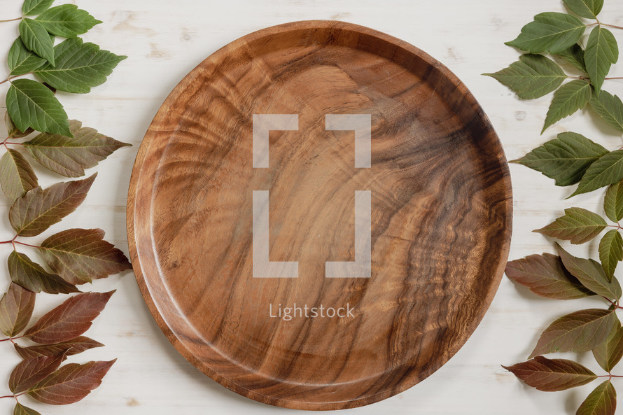 teak tray with red and green leaves on a white wood background 