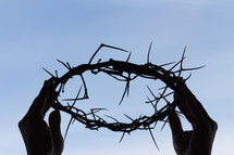 hands holding up a crown of thorns 