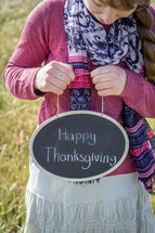 a girl holding a Happy Thanksgiving sign 