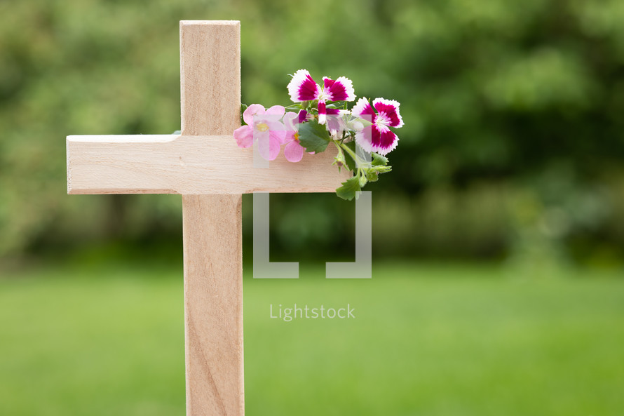 wooden cross with pink flowers outdoors 