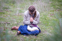 a girl praying over a Bible in her lap 