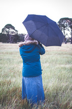 a woman standing outdoors in winter holding an umbrella 