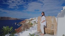 Tourist travel woman in Oia, Santorini, Greece. Young woman on famous landmark destination. Tourist visiting the Greek island.
