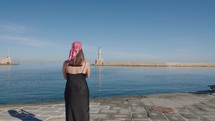 Woman tourist enjoying Bay Of Chania watching the lighthouse In Crete, Greece. 

