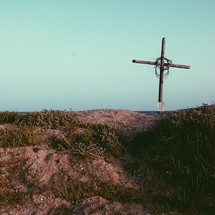 A wooden cross set atop a sand dune.