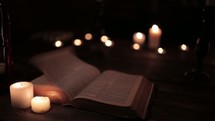 pages flipping on a Bible and flames from votive candles 