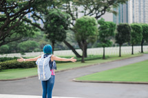 a woman with blue hair standing in a city with outstretched arms 