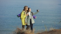 Traveler couple smiling and posing taking selfie using smartphone standing on top of the cliff.