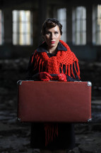 a woman in a red scarf holding a suitcase 