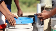 filing buckets of water at a well 