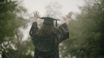 a graduate with hands raised in worship 