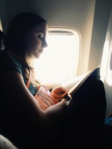 a girl reading on an airplane 