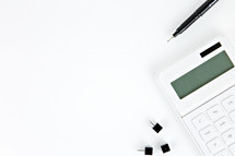 tacks, pen, and calculator on a white desk 