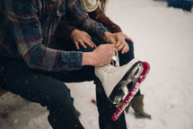 a man tying the laces on a his ice skates 