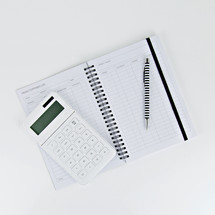 weekly expenses planner, pen, and calculator on a desk 