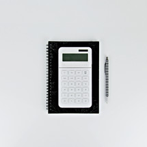 calculator, notebook, and pen on a desk 