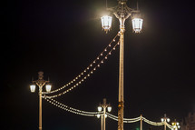 string of lights on street lamps at night 