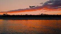 Silhouette Of Airplane take off Over Ocean At Sunset
