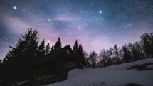 Magic night sky with stars milky way galaxy and clouds motion fast above old wooden hut in wild nature Astronomy time-lapse
