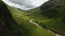 River flowing in a scenic green valley surrounded by mountains and clouds, aerial view Scotland UK