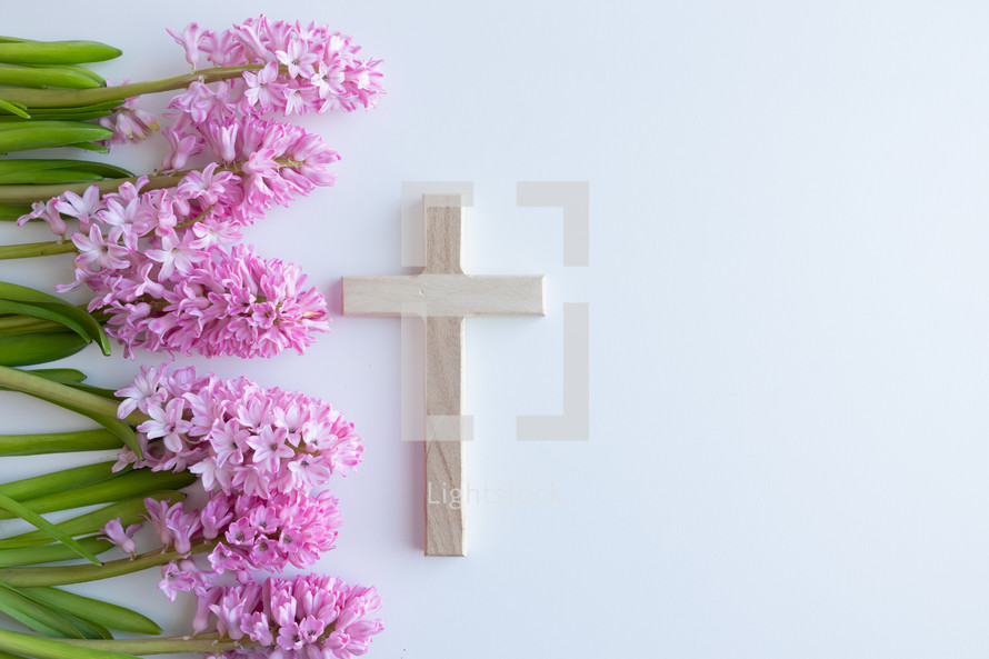 Wooden cross on a white backgrounds with pink flowers