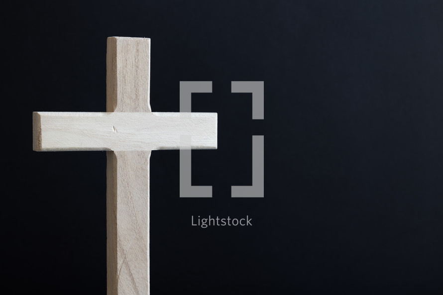 Wood cross standing against a black background