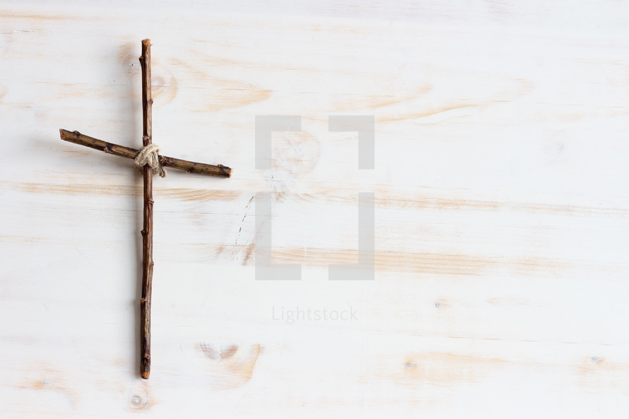 simple cross of sticks on a white wood background 
