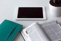 Bible, tablet and house plant on a white background 