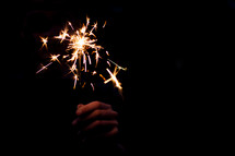hand holding a sparkler in darkness 