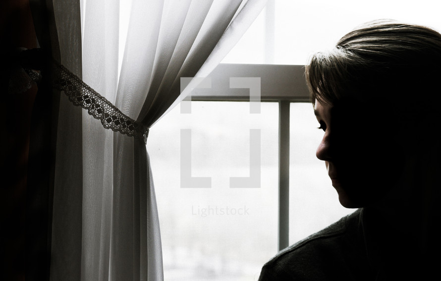 side profile of a woman standing in front of a window 