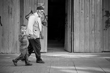 Grandfather and grandson walking on sidewalk
