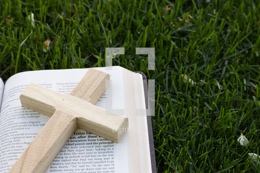 cross on a Bible in the grass