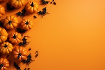 Halloween background with orange pumpkins, spiders and bats on orange background