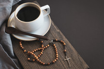 rosary, coffee cup, and wooden spoon on a black background 