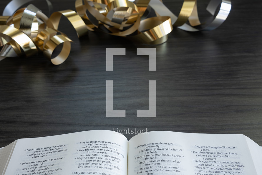 gold streamers and open bible on a dark wood background